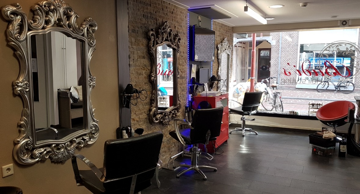 Interieur van Budi’s hairstyling met grote sierlijke spiegels en kappersstoelen